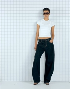 Front full view of woman wearing high-waisted wide-leg denim jeans and a layered white T-shirt
