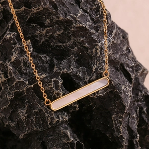 Macro d'un collier barre plaqué or 18K avec nacre blanche sur roche noire brute