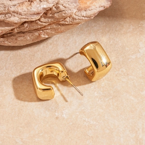 Detailed view of chunky gold-plated C-shaped earrings with mirror-polished finish