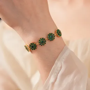 Macro shot of gold-plated flower bracelet with emerald green zircon petals on silk