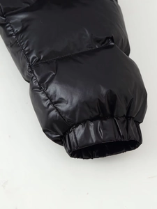 Close-up detail of glossy black padded jacket cuff with elastic ribbed design