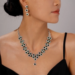 Detail of luxury silver necklace and earrings with green emerald gems and white diamonds