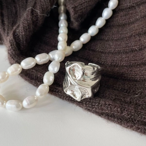 Detail of irregular textured 925 silver ring with liquid metal design and pearl decor