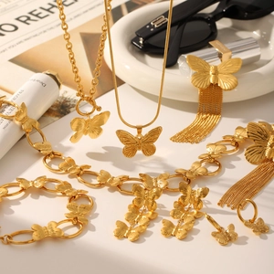 Golden butterfly jewelry set featuring necklace bracelet and earrings on aesthetic background