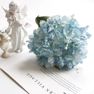 Artistic detail of a large blue and white gradient artificial hydrangea on a white desk