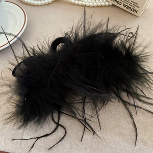 Detailed view of elegant black feather hair claw clip on a textured stone surface