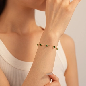 Minimalist gold chain bracelet with five green zircon stones in classic claw setting