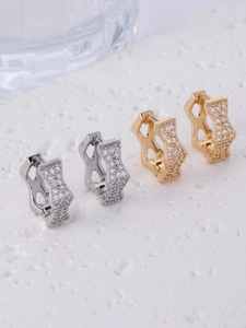 Close-up of geometric pavé crystal earrings in silver and gold on a stone base