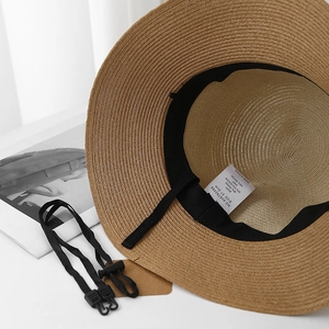 Detail of woven straw hat interior with adjustable strap and material tag showing size