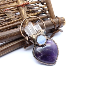Macro detail of handmade copper wire-wrapped heart amethyst and crystal point pendant