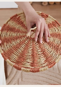 Detail of hand-woven circus basket lid with red-brown spiral patterns and ring handle