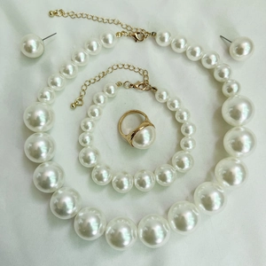 Flat lay of elegant pearl jewelry set including necklace, bracelet, earrings and gold ring