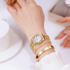 Detailed view of women's gold watch with diamond bezel and white dial on wrist