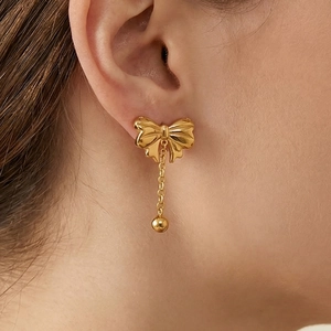 Elegant gold bow earrings with beaded chain drops on model, stylish jewelry set for women