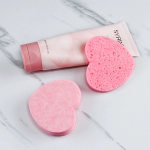 Pink heart-shaped compressed wood pulp sponges with 100ml cleansing tube on marble