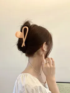 Close-up of minimalist apricot matte hair claw clip holding a stylish hair bun