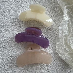 Minimalist jelly colored hair claw clips in cream, purple, and peach on concrete background