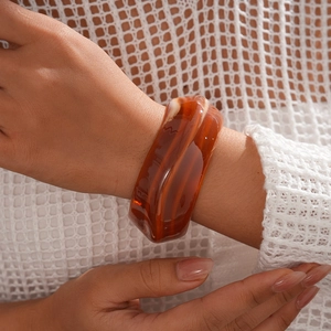 Macro shot of amber acrylic resin bangle with a marbled texture worn by a model