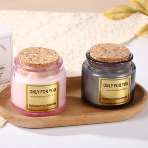 Pink and grey scented candles in glass jars with cork lids on a wooden tray