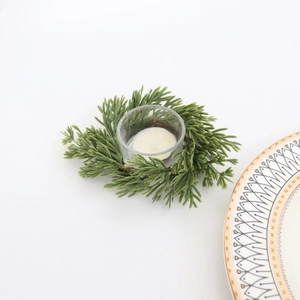 Close-up of pine needle wreath candle holder with clear glass cup and white tea light