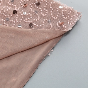 Detail of pink off-shoulder evening dress featuring delicate beadwork and mesh fabric
