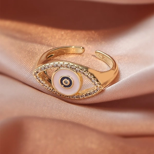 Close-up of golden Evil Eye adjustable ring with crystal pavé on champagne silk
