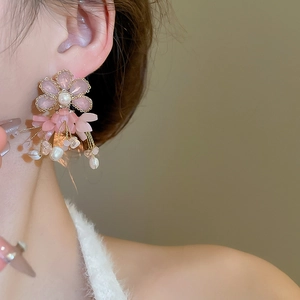 Close-up of pink flower earrings with freshwater pearls and long beaded tassels on model