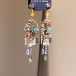 Close-up of golden tassel earrings with multicolored crystals, pearls, and glass beads