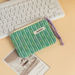 Close-up of green woven mini pouch with colorful stripes and JIMEIZI logo label