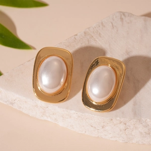 Detailed macro view of vintage gold metallic square earrings with large white pearl inlay