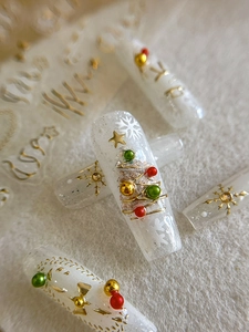 Macro shot of 3D Christmas nail art with festive tree, glitter, and pearl decorations