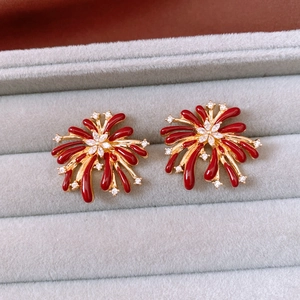 Detail of vintage flower earrings with red enamel petals and zircon crystal center