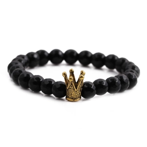 Makro-Detail von 8mm facettierten schwarzen Perlen und goldener Krone auf dem Armband