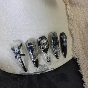 Detailed macro view of Gothic stiletto press-on nails with metal skulls and flame patterns