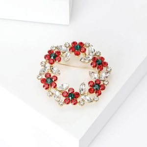 Detailed macro view of the gold rhinestone wreath brooch with red and green floral accents