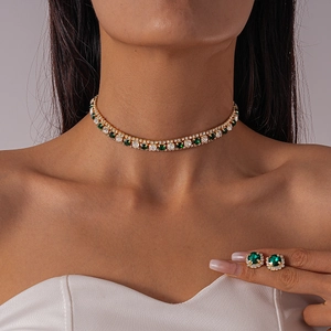 Luxury gold necklace and earring set featuring green emerald and white diamond stones