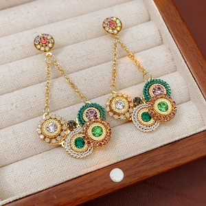 Vue détaillée de boucles d'oreilles vintage en or avec strass colorés dans un coffret