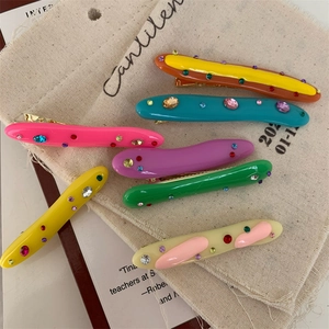 Colorful irregular acrylic hair clips with rhinestones set on a beige canvas background