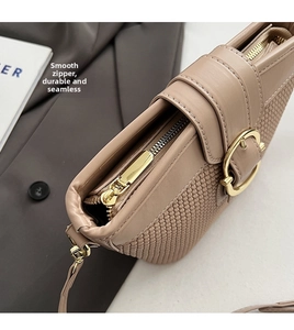 Detail shot of smooth golden zipper and woven texture on beige faux leather bag