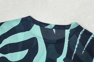 Detailed close-up of crew neck collar featuring abstract striped knit texture in deep teal