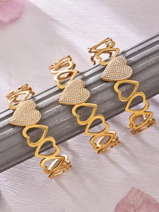 Close-up of three gold open bangles featuring hollow hearts and micro-pave zircon crystals