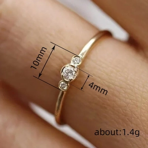 Bague dorée minimaliste sertie de trois zircons avec pierre centrale ronde de 4mm poli