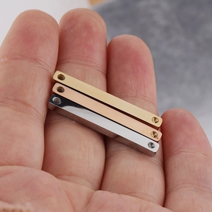 Three polished stainless steel bar pendants in gold, rose gold and silver on palm