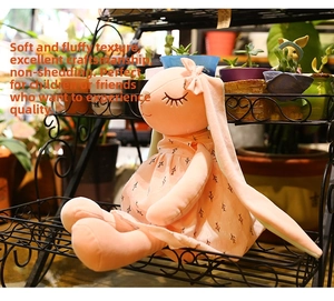 Close-up of pink lop-eared bunny plush in a floral dress on a black plant stand