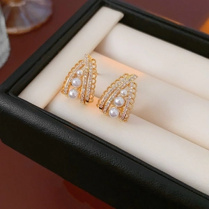 Macro shot of vintage gold earrings featuring lace design with pearls and sparkling zircons