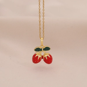 Detailopname van een gouden aardbei hanger ketting met rood en groen emaille coating