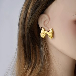 Elegant 18k gold plated stainless steel bow stud earrings shown on female model