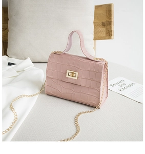 Détail du sac rose clair motif crocodile avec fermoir rotatif doré et bandoulière