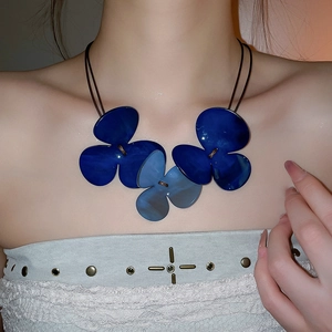 Detail of three oversized deep blue resin flower pendants on a double-strand cord necklace