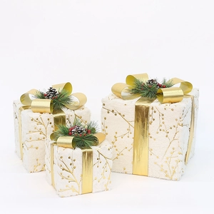 Detailed view of plush white Christmas gift boxes with gold ribbons and pine cone accents